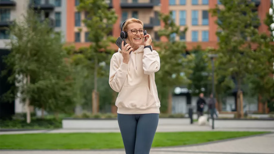 Een dame in een Belgisch stadslandschap die luistert naar de podcast over de energietransitie van veb