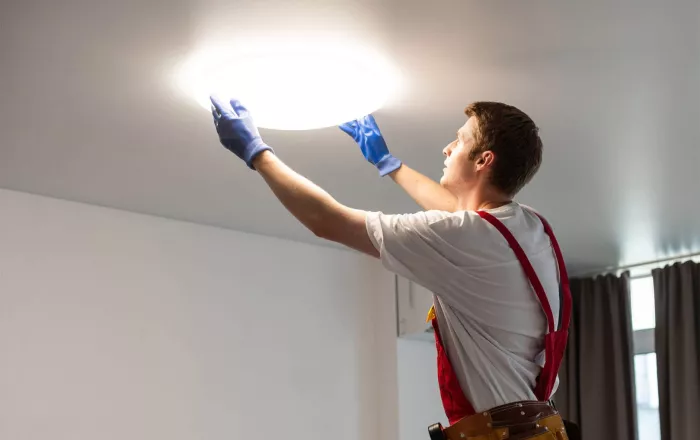 Een technieker vervangt een lamp in een wooneenheid.